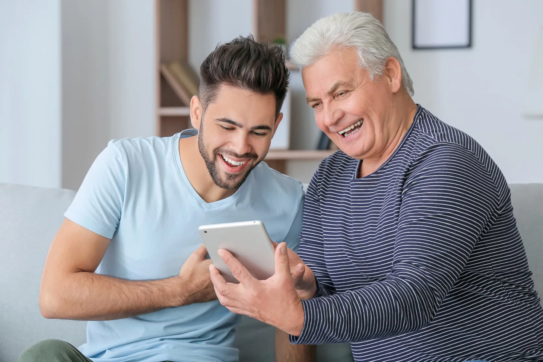Adult son and his father reading a tablet together